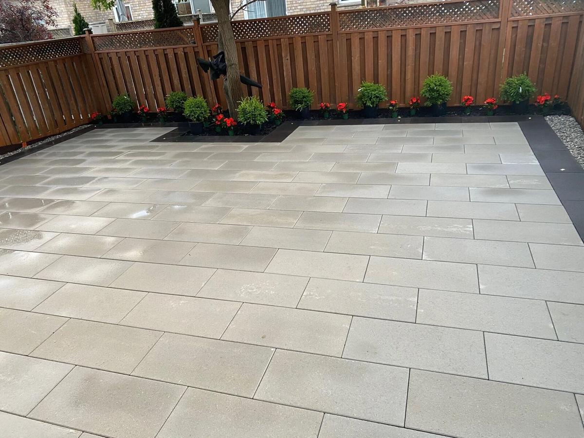 Large grey slab patio with a planted border